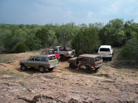 1996 Ford Bronco - A group of SUVs and a pickup truck are parked off-road in a natural, rocky environment.