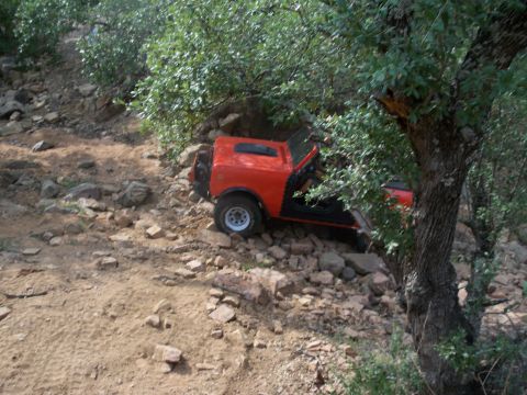 1996 Ford Bronco - An orange off-road vehicle navigates a rocky, wooded trail.
