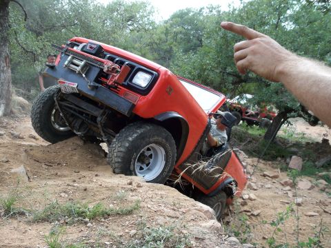 1996 Ford Bronco - An off-road vehicle navigates a steep dirt incline, with another vehicle visible in the background.