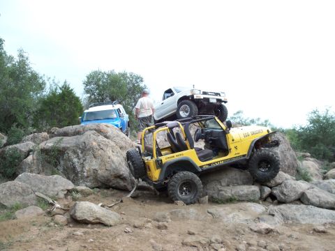 1996 Ford Bronco - Multiple off-road vehicles tackle a challenging rocky landscape, with a yellow Jeep in the foreground and a white Toyota pickup truck perch…