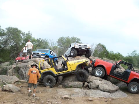 1996 Ford Bronco - Multiple off-road vehicles navigate a challenging rocky landscape under an overcast sky.
