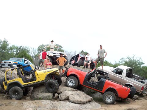 1996 Ford Bronco - Several off-road vehicles and their drivers are gathered on a rocky landscape, posing for a photo.