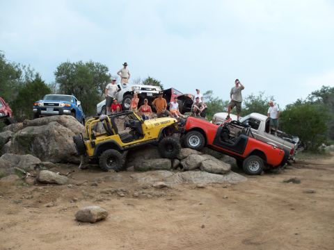 1996 Ford Bronco - Several off-road vehicles are positioned on a rocky terrain with people gathered around.