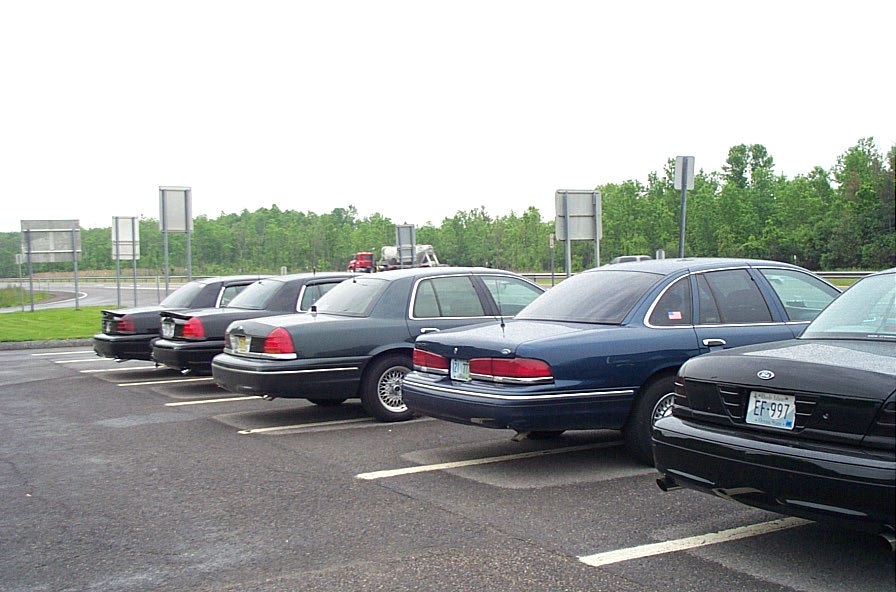 Several Ford Crown Victoria police cars parked in a lot, rear view