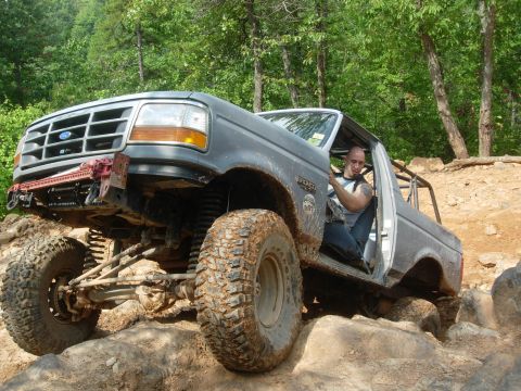 1995 Ford Bronco - Driver maneuvers a modified 1995 Ford Bronco over large rocks on a trail.