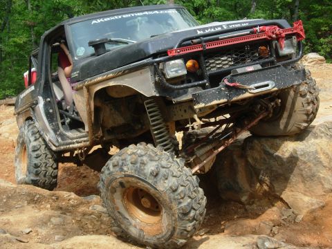 1995 Ford Bronco - This heavily modified off-road vehicle is shown tackling a challenging rocky trail.