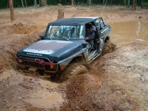 1995 Ford Bronco - A modified off-road vehicle navigates a challenging mud obstacle.