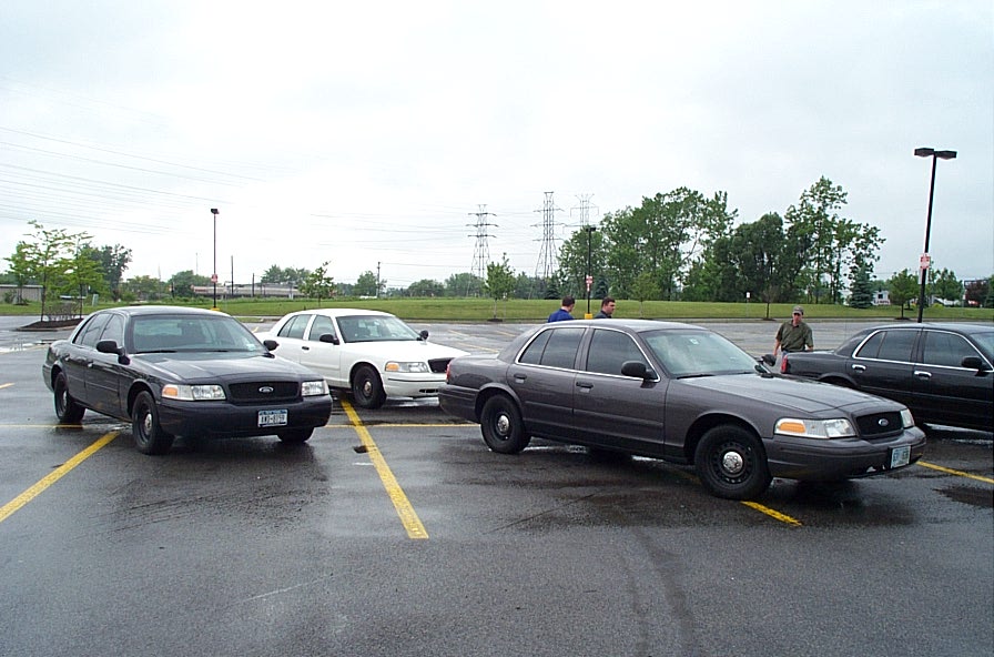 Dark sedan parked in a lot, front quarter view. Visible license plate and side mirror
