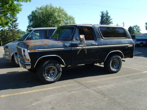 1978 Ford Bronco - Side view of a black 1978 Ford Bronco with a rusty hood, parked outdoors.