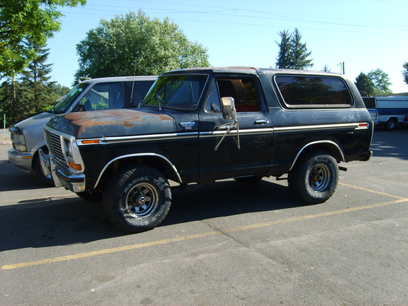 1978 Ford Bronco parked next to a van, showing rust on the hood