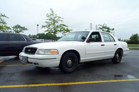 1991 Ford LTD Crown Victoria - A white Ford Crown Victoria is parked in a wet lot next to another car.