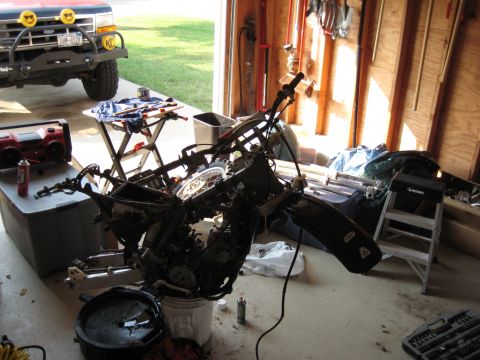 1993 Suzuki RMX250 - Motorcycle parts laid out in a garage, with a truck in the background.