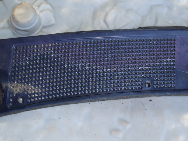 Dark blue plastic windshield cowl grille with many small holes