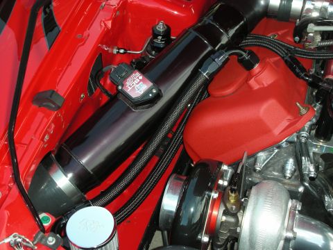 1998 Ford Crown Victoria - Close-up of a modified engine bay a turbocharger, custom intake, and red valve cover.