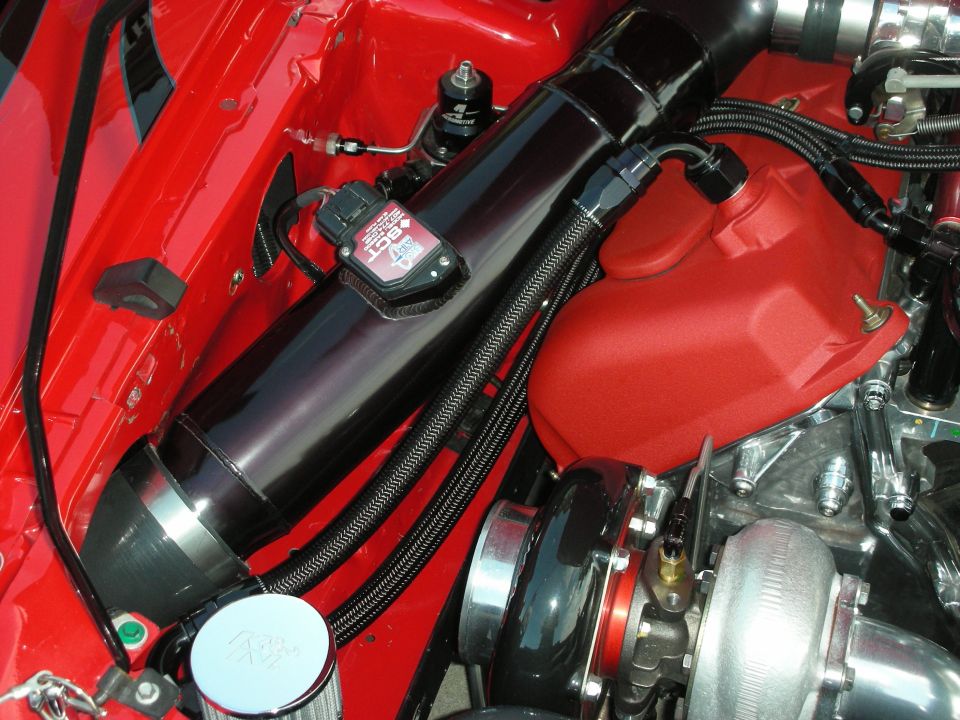 Engine bay with turbocharger, intake tube, and red valve cover