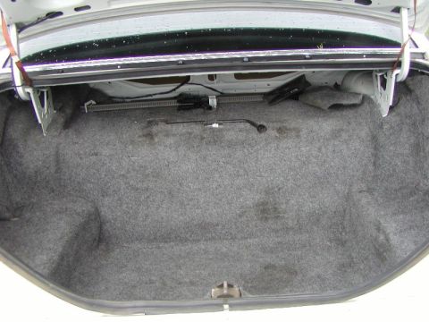 1991 Ford LTD Crown Victoria - Open trunk of a white full-size sedan viewed from directly behind, showing a clean gray carpeted cargo floor and trunk sides. The factory j…