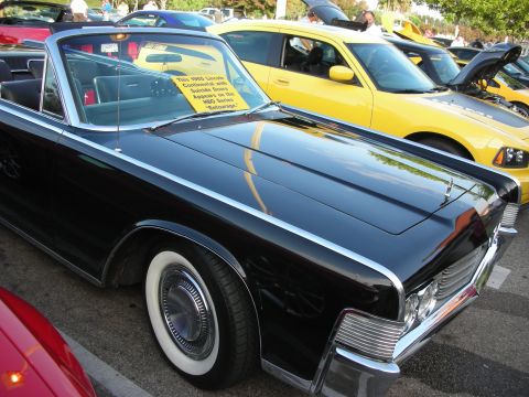 1998 Ford Crown Victoria - A classic black Lincoln Continental convertible is parked next to a modern yellow Dodge Charger at a car meet.