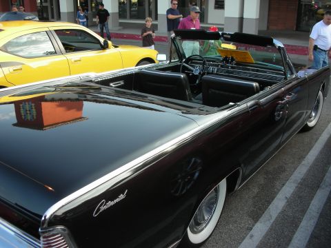 1998 Ford Crown Victoria - A black convertible with whitewall tires is parked next to a yellow sedan.