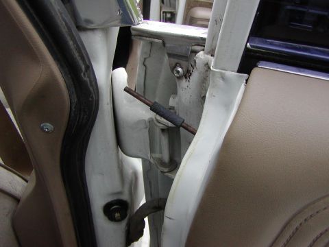 1991 Ford LTD Crown Victoria - Close-up view of the interior door hinge mechanism, showing a metal rod with a rubber sleeve.