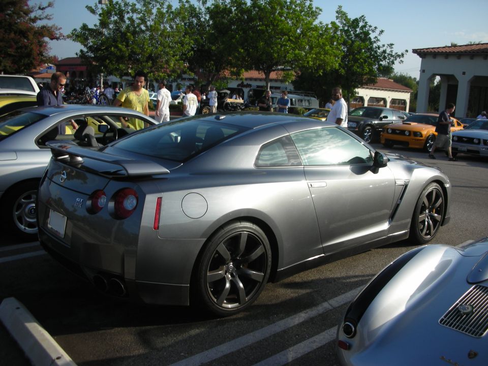 Gray Nissan GT-R parked next to other cars at an outdoor meet