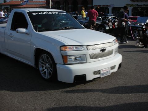 1998 Ford Crown Victoria - A white Chevrolet Colorado pickup truck is parked at an outdoor event with other vehicles and people.