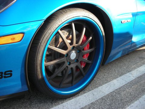1998 Ford Crown Victoria - A bright blue sports car features custom wheels with a striking blue accent ring and red brake calipers.