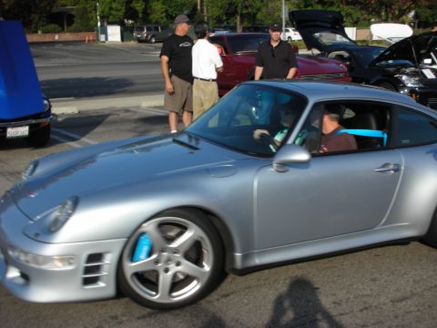 1998 Ford Crown Victoria - A silver Porsche 911 is parked at an outdoor gathering with other vehicles and people around.