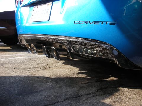 1998 Ford Crown Victoria - The rear of a blue Corvette shows a carbon fiber diffuser and quad exhaust pipes.