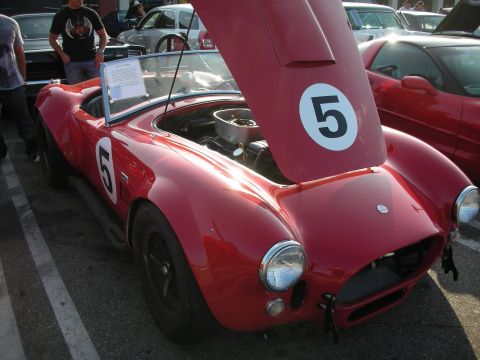 1998 Ford Crown Victoria - A red sports car, possibly a Cobra replica, is displayed with its hood open, racing numbers on the hood and door.