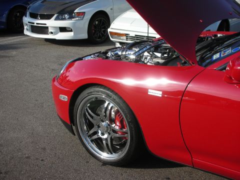 1998 Ford Crown Victoria - A red sports car is parked with its hood open, revealing the engine, alongside other vehicles.