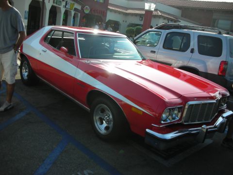 1998 Ford Crown Victoria - A red and white 1977 Ford Gran Torino coupe is parked next to a silver SUV.
