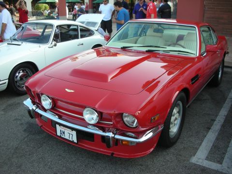 1998 Ford Crown Victoria - A red coupe with a hood scoop and chrome bumper is parked next to a white car.