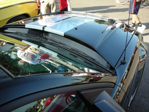 1998 Ford Crown Victoria - A black car with racing stripes is parked next to a yellow car at an outdoor event.