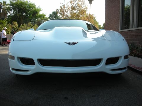 1998 Ford Crown Victoria - A white Chevrolet Corvette C5 is parked outside a brick building on a sunny day.