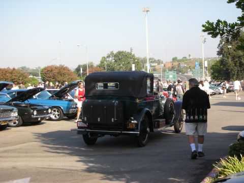 1998 Ford Crown Victoria - A dark green vintage convertible is parked at an outdoor car meet, with other vehicles and people around.