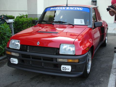 1998 Ford Crown Victoria - A red Renault 5 Turbo is parked outside, with a photographer in the background.