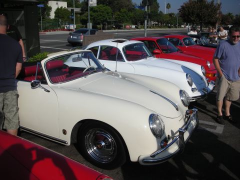 1998 Ford Crown Victoria - A line of classic cars, including a white convertible and a red coupe, are parked together at an outdoor event.