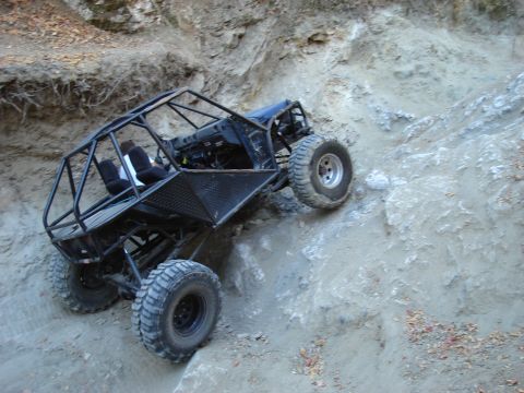 1985 Toyota Hilux - This custom off-road buggy navigates a challenging incline on a dirt trail.