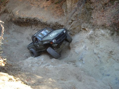 1985 Toyota Hilux - Off-road pickup truck with military-style markings climbs a challenging rocky terrain.