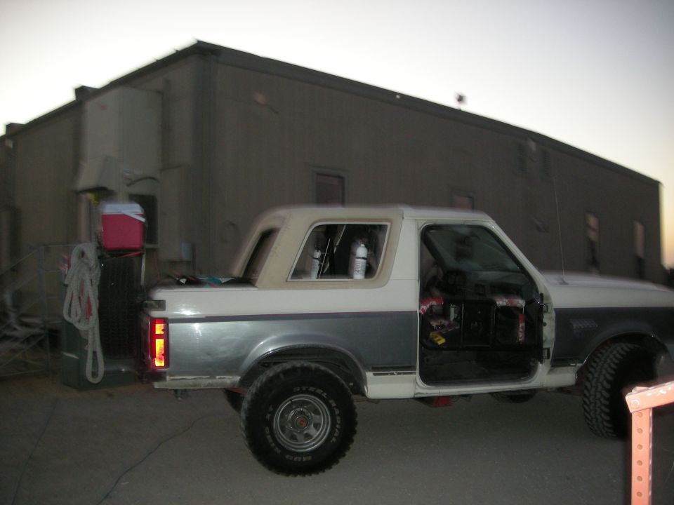 1991 Ford Bronco with doors removed, parked outside a building