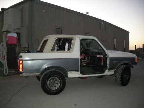 1991 Ford Bronco - A 1991 Ford Bronco is seen with its doors open, parked in front of a building.