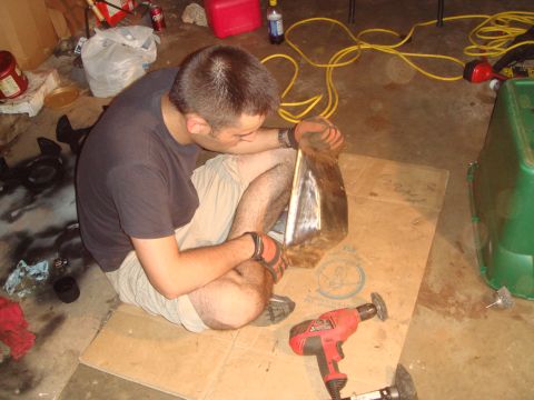1992 Ford Bronco - A person is shown working on a metal component, possibly a car part, in a garage setting.