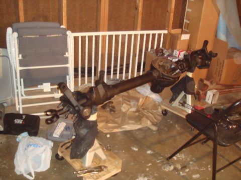1992 Ford Bronco - A disassembled front axle assembly is shown supported by jack stands in a cluttered garage setting.