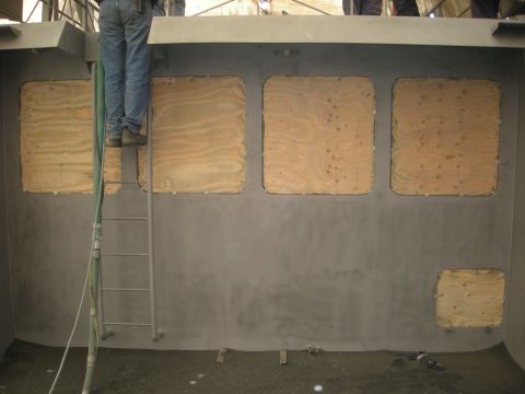 1991 Ford Bronco - A person stands on a ladder inside a vehicle where windows are covered with plywood.