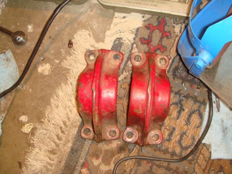 1992 Ford Bronco - Two red bearing caps sit on a cluttered floor next to a wrench and some debris.