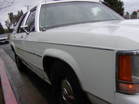 1991 Ford LTD Crown Victoria - Side view of a 1991 Ford Crown Victoria LTD, parked on a wet street.