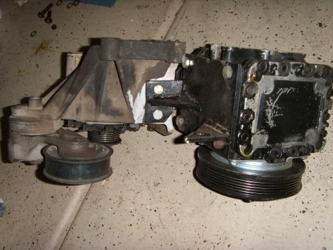 1989 Ford F-250 - Air conditioning compressor assembly with mounting bracket and pulleys, likely removed from a vehicle for repair or replacement.
