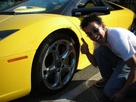 1998 Ford Crown Victoria - A man poses with a bright yellow Lamborghini, giving a thumbs-up gesture.