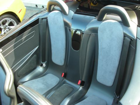 1998 Ford Crown Victoria - The interior of a black sports car with grey seats and carbon fiber accents, with a yellow car partially visible on the left.
