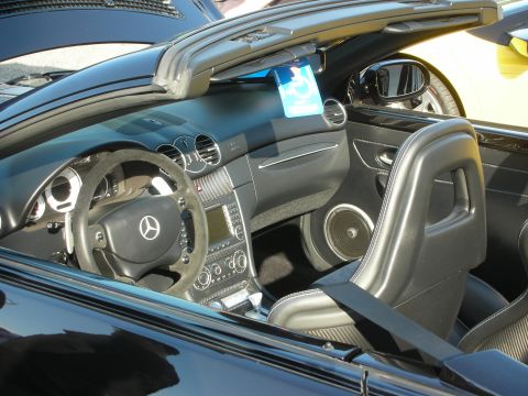 1998 Ford Crown Victoria - The interior of a black convertible is visible, a Mercedes-Benz steering wheel and a blue handicap parking permit hanging from the rearview…